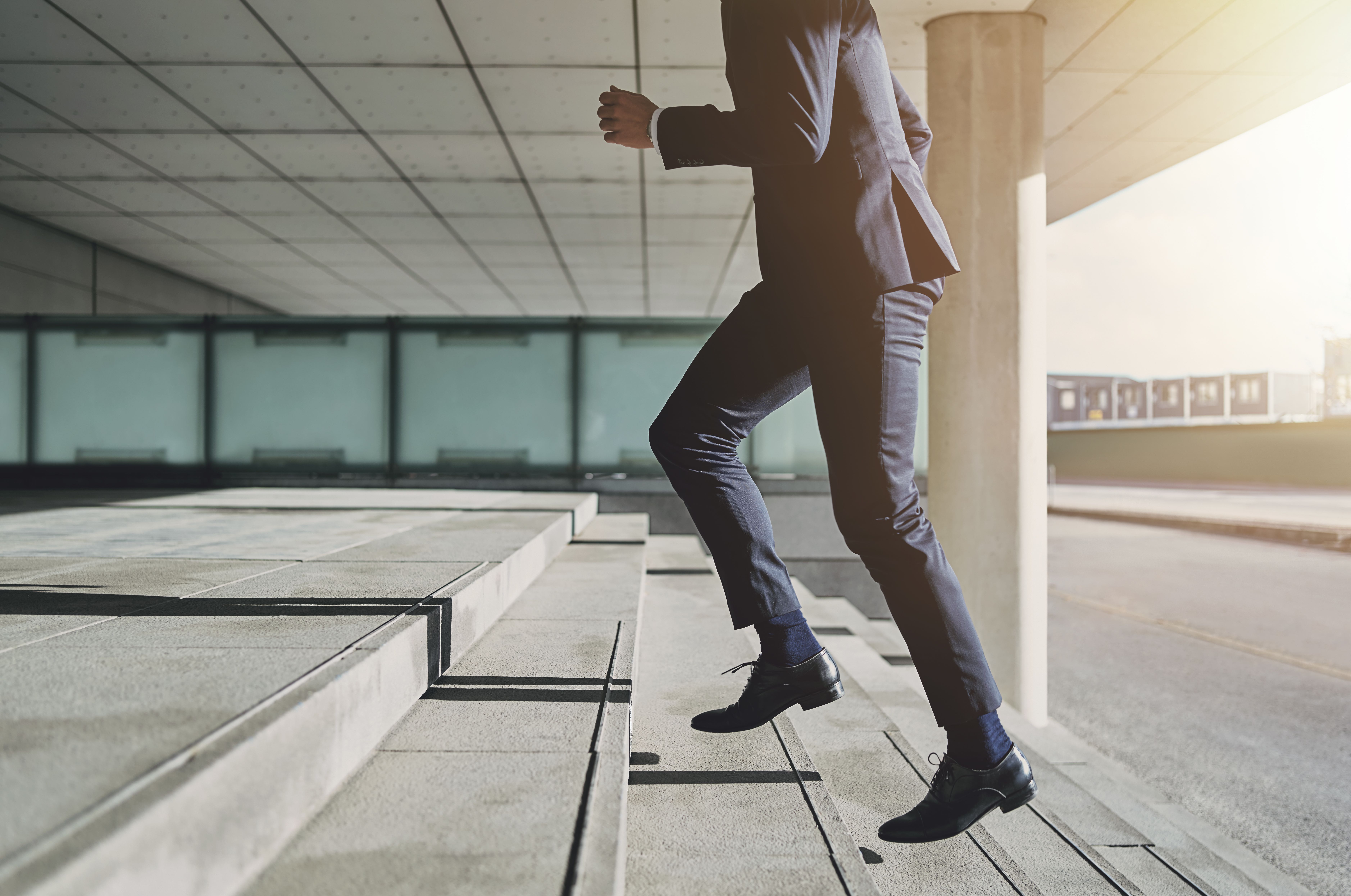 Man wearing suit runs up the stairs Businessman running fast upstairs. Horizontal outdoors shot.